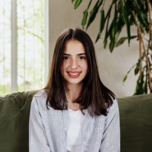 beautiful smiling caucasian girl sitting at green sofa and watching at camera.jpg
