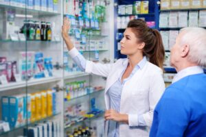 beautiful young woman pharmacist showing drugs to senior man customer in pharmacy .jpg